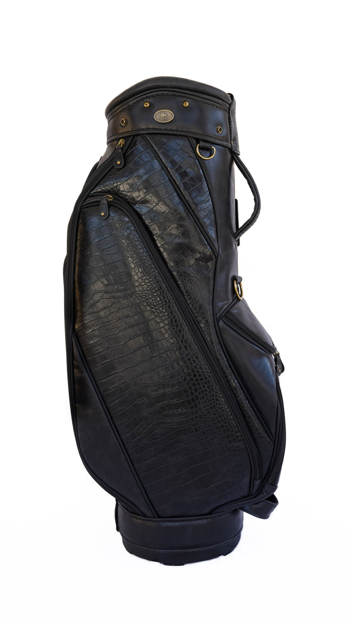 A black leather golf bag with a textured crocodile pattern on the front panel, featuring gold-tone hardware and a top strap, shown against a plain white background.