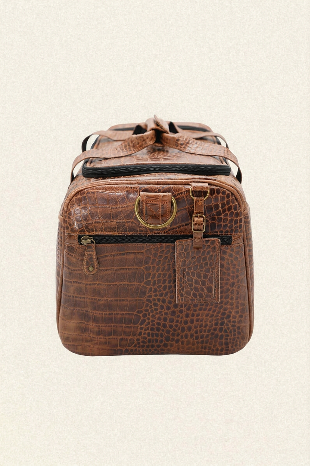A brown crocodile-embossed leather duffel bag with brass hardware, shown from the front against a light beige textured background.