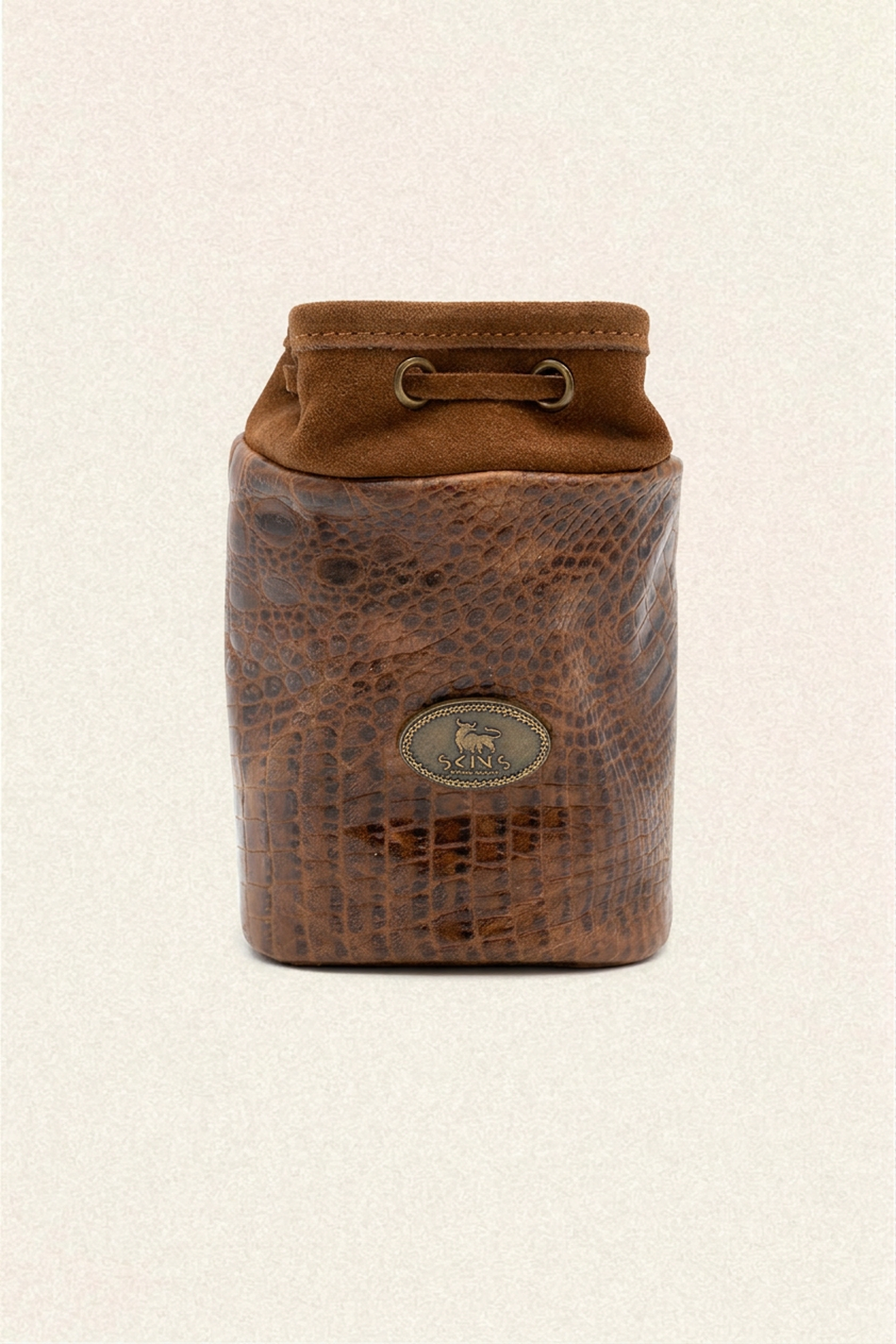 A brown leather pouch with a textured crocodile pattern body and a smooth suede-like top flap, featuring a metal horse logo medallion on the front and a drawstring closure at the top, set against a light beige background.