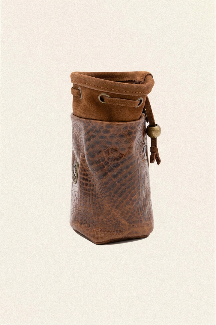 A brown leather pouch with a textured python-patterned front and a suede-like drawstring top, shown on a light beige textured background.