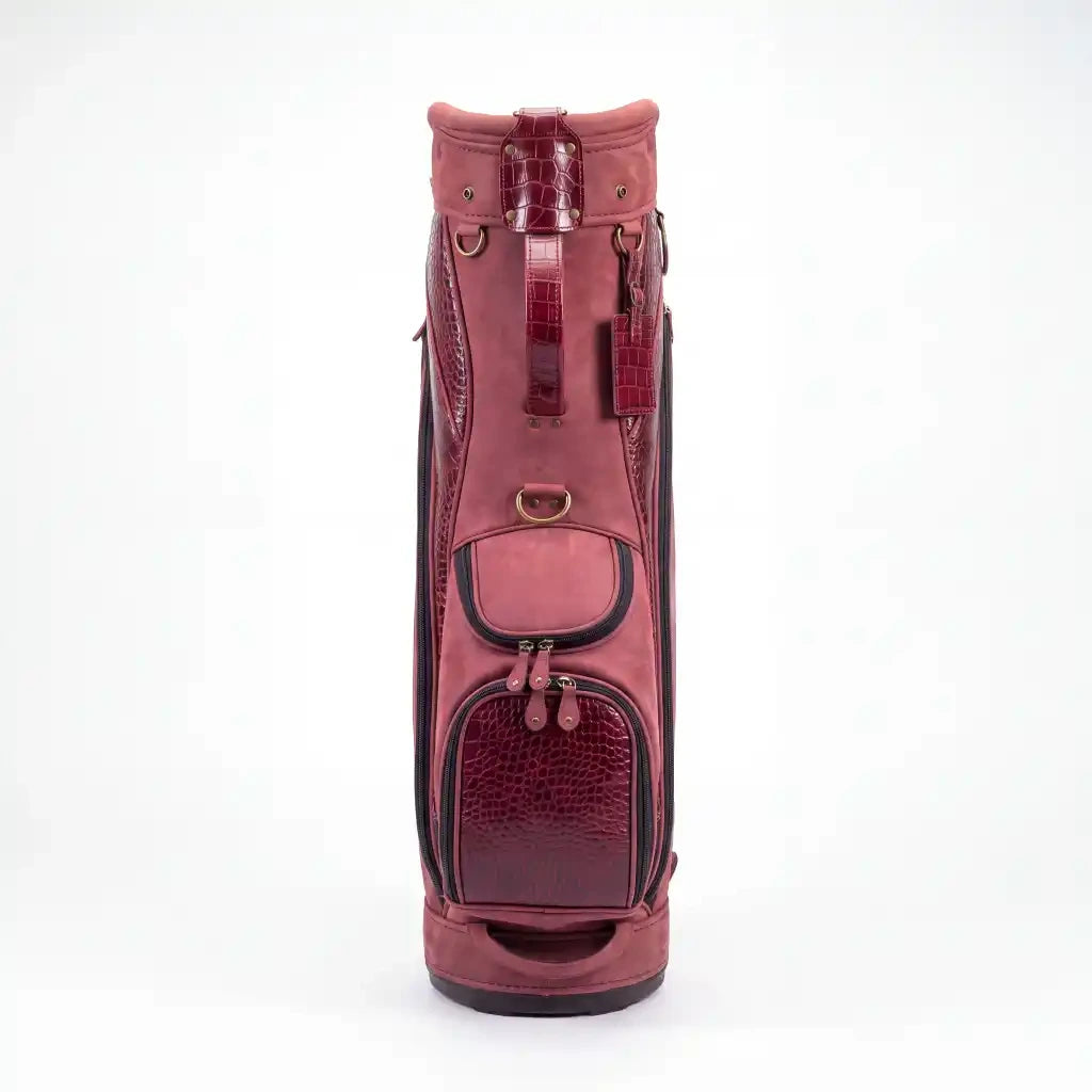 A pinkish-red leather golf bag with textured crocodile-embossed panels and black trim, shown against a plain white background.