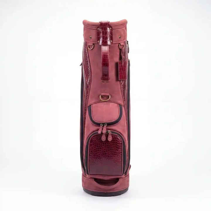A pinkish-red leather golf bag with textured crocodile-embossed panels and black trim, shown against a plain white background.