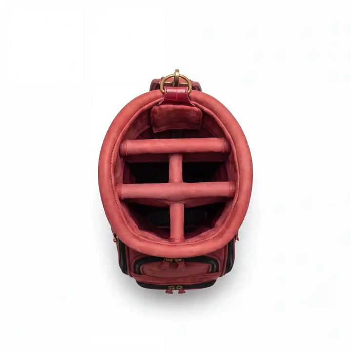 A top-down view of a dusty rose pink leather golf bag, showing the interior with a crossbar divider and gold-tone hardware on a white background.