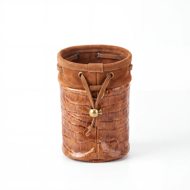 A brown leather cylindrical bucket bag with a crocodile-embossed texture on the lower half, a smooth suede-like upper band, and a drawstring closure with a gold-tone bead accent, shown on a white background.