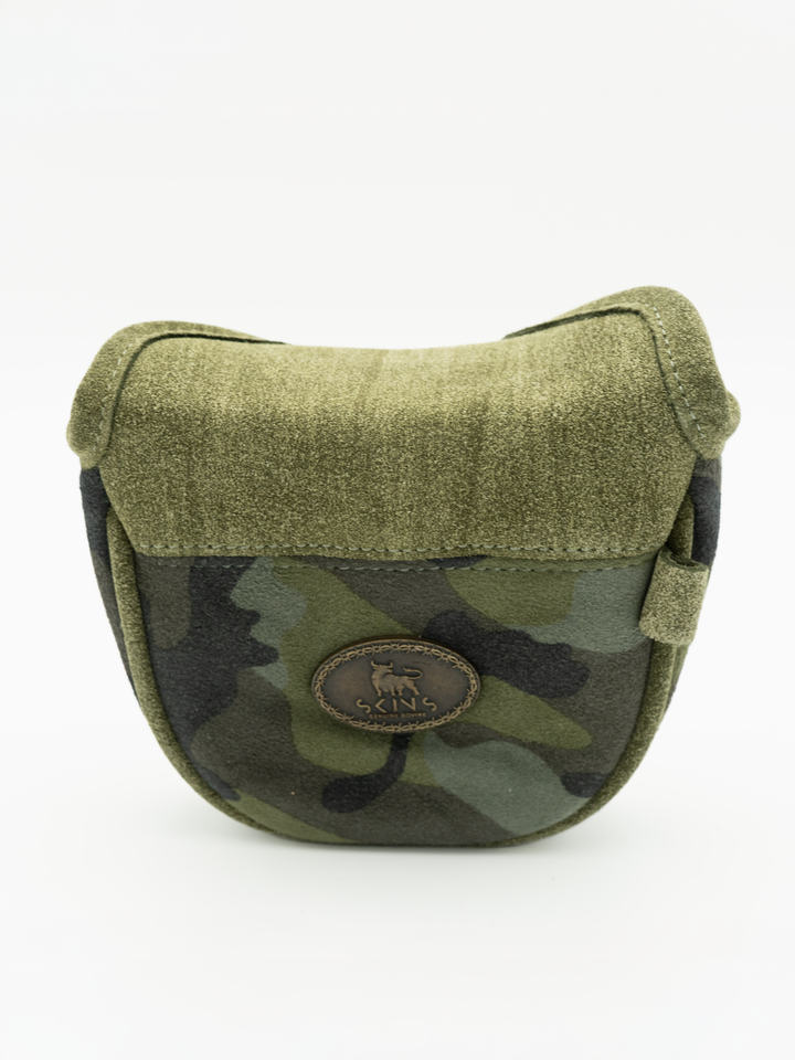 An olive green and black camouflage shoulder bag with a textured fabric flap and a circular brown logo patch on the front, set against a plain white background.