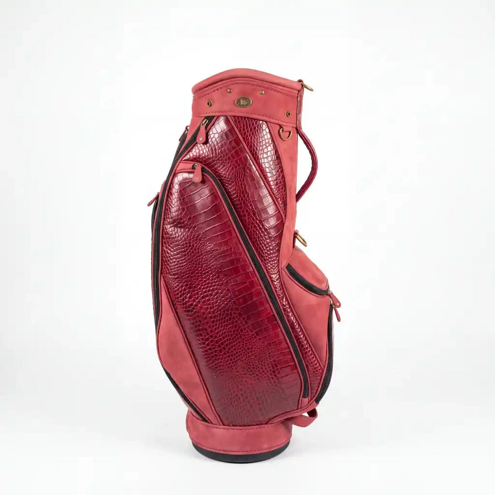 A red leather golf bag with crocodile-embossed panels and black piping, shown from a side profile on a white background.