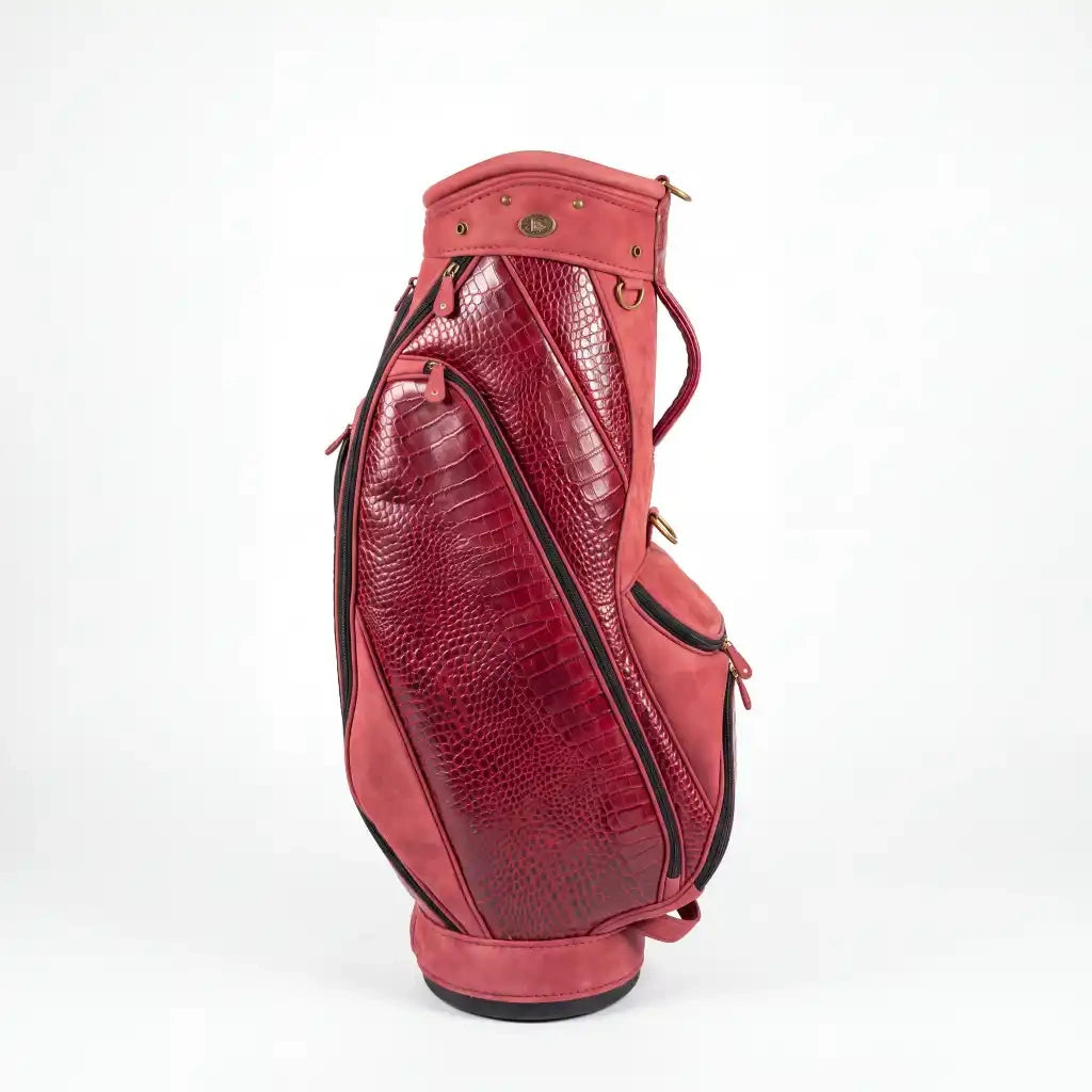 A red leather golf bag with crocodile-embossed panels and black piping, shown from a side profile on a white background.