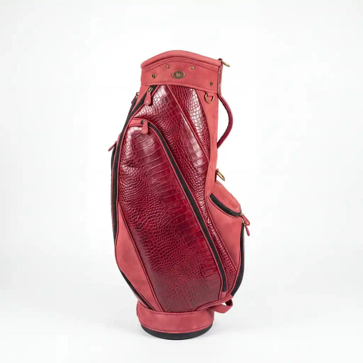 A red leather golf bag with crocodile-embossed panels and black piping, shown from a side profile on a white background.